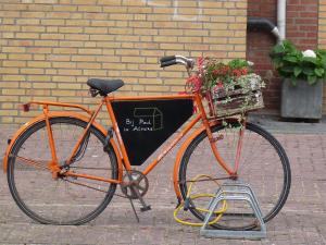 阿尔梅勒Bij Paul in Almere的一辆橙色自行车,装满鲜花篮子