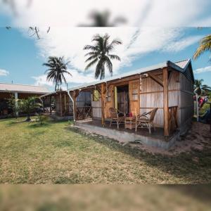 Rodrigues IslandGravier beach house的一座带门廊和两棵棕榈树的小木房子