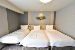 秋田秋田站前里士满酒店的客房内的两张床,墙上配有白色床单和气球