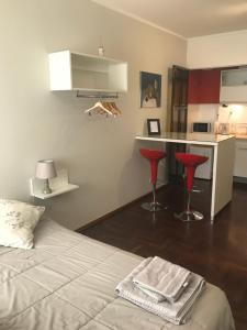 布兰卡港Lindisimo depto centro Bahía的一间卧室配有一张床,厨房配有红色凳子