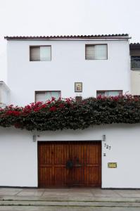 利马Jose Luis Hostal Boutique的白色的建筑,有木门和红色的鲜花