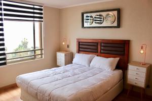 伊基克Departamento Jardines de Huayquique的一间卧室设有一张大床和一个窗户。