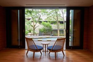 箱根箱根优托瓦酒店(Hakone Yutowa)的一个带游泳池的房间里设有两把椅子和一张桌子