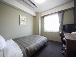 妙高鲁特酒店 - 妙高新井旅馆的配有一张床、一张书桌和一扇窗户的酒店客房