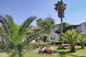 斯卡拉卡伦尼斯玛莱米有机酒店的一座种有棕榈树和桌子的花园以及一座建筑