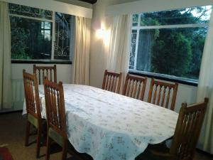 温特顿Ondini Guest House的一间带桌椅和2扇窗户的用餐室