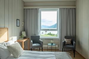 肖伦Skjolden Hotel的一间卧室配有一张床、两把椅子和一个窗户