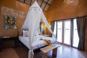 珀尼达岛Pondok Kana And Hostel by Ecommerceloka的一间卧室配有一张带蚊帐的床