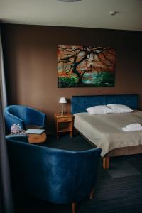 库尔迪加Comfort Hotel Kuldiga的一间卧室配有一张床和一张蓝色椅子