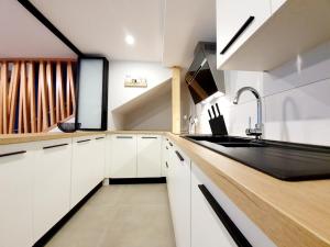 希伯维列Mes Amours的厨房配有白色橱柜和黑色水槽