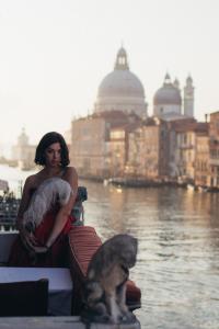 威尼斯大运河皮萨尼宫酒店的船上抱着婴儿和狗的女人