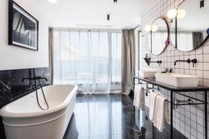 马德里万夏特福尔图尼07酒店的浴室配有两个盥洗盆和浴缸。