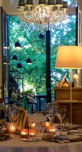 波佩林赫Charmehotel Manoir Ogygia的桌子,带玻璃杯和灯,窗户