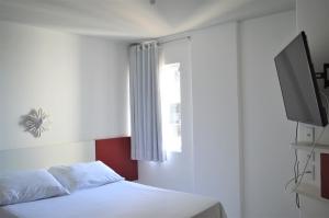 马塞约Apart Cote D'Azur Maceió的卧室配有白色的床和电视。