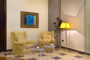 索伦托乌利赛豪华旅馆的一间设有两把椅子、一张桌子和一盏灯的房间