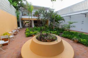 蒙波斯La Gloria Hotel by BespokeColombia的一座带庭院的建筑,庭院里种有植物,配有桌椅