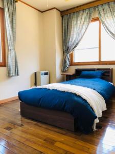 野沢Apartment at Toemu Nozawa的一间卧室设有一张大蓝色的床和窗户