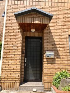 野沢Apartment at Toemu Nozawa的砖砌的建筑,有一扇带窗户的黑色门