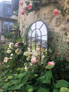 翁弗勒尔La Cour Sainte Catherine demeure de charme的一块石头墙前的玫瑰