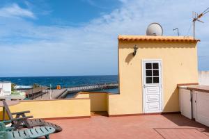 圭马尔港Casita de playa的一座黄色的建筑,有白色的门和大海