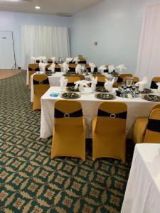 塔拉迪加经济套房旅馆 - 塔拉迪加的一间设有桌椅、白色桌子和黄色椅子的房间