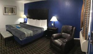 俄克拉何马城Budget Inn & Suites的配有一张床和一把椅子的酒店客房