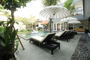 坎古坎古冲浪酒店的一座带椅子和遮阳伞的游泳池位于一座建筑旁边