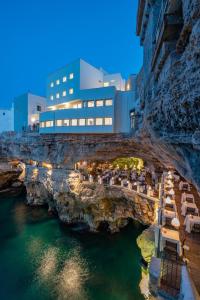 滨海波利尼亚诺Hotel Grotta Palazzese的夜间在水边的悬崖上的餐厅