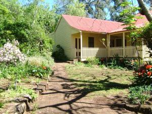 Kurrajong冬宫小屋住宿加早餐旅馆的黄色的房子,有红色的屋顶和花园