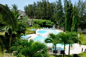 马林迪Amani Residence Beverly Suites的一个带蓝色椅子的游泳池,棕榈树