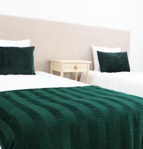 瓜尔达COLD CITY HOUSE的两张带绿色和白色床单的床以及一张桌子