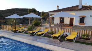 阿洛拉Villa Rural El Mirador的房屋旁的游泳池配有椅子和遮阳伞