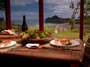 Bethells Beach贝索斯海滩公寓式酒店的一张桌子,上面放着一盘食物和沙拉