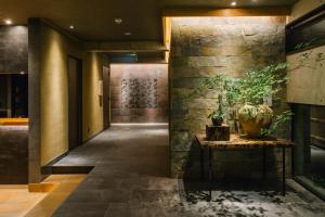 京都Higashiyama Shikikaboku的走廊上设有石墙和盆栽桌子