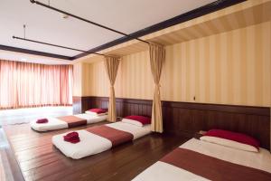 彭世洛The Imperial Hotel & Convention Centre Phitsanulok的配有木地板和窗帘的客房内的三张床