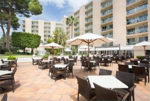 帕尔马海滩东方集团酒店的一个带桌椅和遮阳伞的户外庭院。