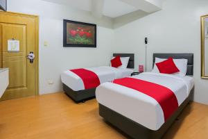 马尼拉OYO 190 Anglo Residences的一间卧室配有两张红色和白色床单
