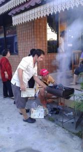 班武里府สุขทวีรีสอร์ท อ่าวมะนาว的一个人在烧烤架上做饭