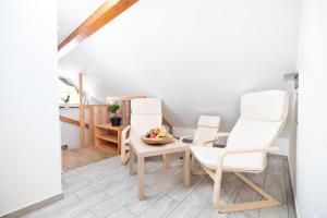 ŽirovnicaApartment & room Pristov的一间设有三把白色椅子和一张桌子的房间