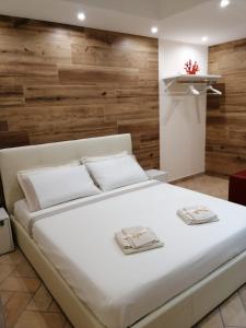 SquinzanoDimora Tra I Due Mari的卧室配有一张白色大床和木墙