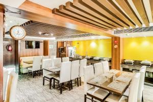 钦奈Saibala Grand Airport Hotel的一间带桌椅和时钟的用餐室