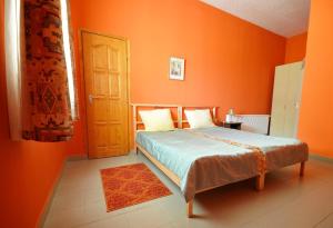 GaraboncGergely Tanya的一间卧室拥有橙色的墙壁,设有一张床和一扇门