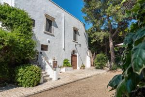 孔韦尔萨诺Masseria Santo Stefano Relais&Charming House的灰色的建筑,有棕色的门和树木
