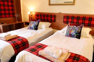 卡伦德Highland House Callander的配有两张床铺的酒店客房 - 带拼盘枕头