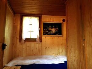 CrésuzCharmant Petit Chalet 3 étoiles en Gruyère的木制客房的一间卧室配有一张床,设有窗户