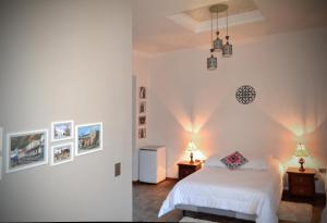 基多TRAVELER'S HOUSE QUITO的一间卧室配有一张白色的床和两张带台灯的桌子。