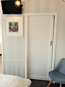 坎布里奇66 Chaucer B&B with Complimentary Breakfast to Go Bag的一间卧室设有一扇门、椅子和电视