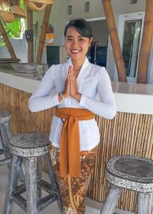 海神庙Coco Verde Bali Resort的坐在凳子上的女人,手放在前面