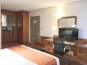 莫尔兹比港莫尔兹比港套房酒店的一间卧室配有一张床、一张书桌和一台电视