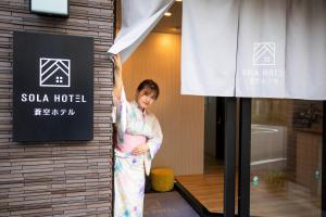东京SOLA HOTEL的站在窗边的和服上的女人